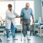 Fisioterapista sorridente aiuta un paziente con emiplegia post-ictus a camminare indossando un tutore AFO bianco in una clinica riabilitativa moderna e luminosa, obiettivo 50mm, luce calda e naturale, profondità di campo che sfoca leggermente lo sfondo.