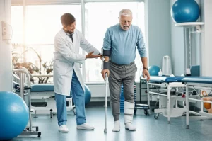 Fisioterapista sorridente aiuta un paziente con emiplegia post-ictus a camminare indossando un tutore AFO bianco in una clinica riabilitativa moderna e luminosa, obiettivo 50mm, luce calda e naturale, profondità di campo che sfoca leggermente lo sfondo.