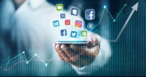 Immagine concettuale che mostra una mano che tiene uno smartphone con icone di social media luminose fluttuanti, sovrapposta a una grafica astratta e dinamica che rappresenta grafici stilizzati di engagement e soddisfazione lavorativa in crescita, ambientata in un contesto aziendale moderno e sfocato. Illuminazione drammatica high-key, obiettivo macro 100mm per dettaglio estremo sulle icone e sulla mano, colori vivaci ma professionali (blu, verde, bianco).