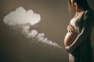 Immagine simbolica: una donna incinta protegge amorevolmente il suo pancione, sfondo leggermente sfocato con una nuvola stilizzata di fumo in lontananza che si dissolve, luce calda e protettiva, obiettivo 50mm, profondità di campo.