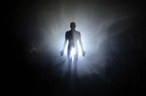 Immagine concettuale che mostra una silhouette umana luminosa emergere da uno sfondo scuro e confuso che rappresenta il dolore cronico, l'ansia e la depressione. La luce simboleggia la speranza e il sollievo portati da un nuovo trattamento come la Dexmedetomidina. Stile fotografico con effetti di luce, obiettivo 35mm, profondità di campo.