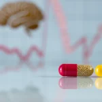 Primo piano di capsule di Trimetazidina e Olanzapina affiancate su una superficie riflettente da laboratorio, con sfondo sfocato di grafici stilizzati rappresentanti l'attività cerebrale e muscolare. Obiettivo macro 100mm, alta definizione, illuminazione controllata e precisa che crea riflessi morbidi.