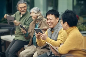 Fotografia realistica stile ritratto di un gruppo eterogeneo di residenti cinesi che interagiscono felicemente sia online tramite smartphone e tablet che di persona in uno spazio comunitario urbano luminoso e moderno, obiettivo prime 35mm, colori caldi duotone (giallo ocra e grigio ardesia), profondità di campo che mette a fuoco i volti sorridenti.