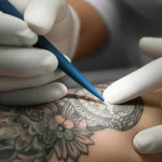 Immagine fotorealistica, obiettivo macro 60mm, primo piano di un tatuaggio vibrante sulla pelle accanto alla luce di esame di un dermatologo, alta definizione, messa a fuoco precisa, illuminazione controllata, suggerendo un controllo sanitario.