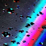 Foto macro ad alta definizione di un fascio di luce digitale multicolore (DigiBeams) che illumina una superficie metallica con micro-difetti, mostrando la riflessione colorata che ne rivela la forma. Obiettivo macro 90mm, illuminazione precisa, alta definizione, tecnologia DigiBeams.
