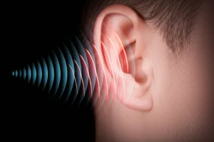 Primo piano fotorealistico di un orecchio umano con onde sonore stilizzate che emanano verso una mascella tesa, illuminazione controllata, obiettivo macro 60mm, alta definizione, a simboleggiare il legame tra acufene e disturbi orofacciali.