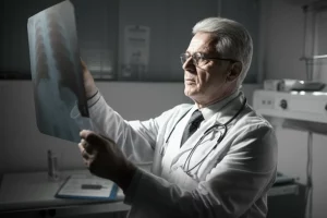 Fotografia in stile ritratto, primo piano di un medico anziano con occhiali che esamina con attenzione una radiografia addominale in una stanza d'ospedale poco illuminata, obiettivo 35mm, profondità di campo, bianco e nero.