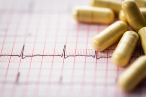 Primo piano di capsule di antidepressivi sparse su un elettrocardiogramma (ECG), simboleggiando il legame tra farmaci per la depressione e la salute cardiaca. Macro lens, 100mm, high detail, precise focusing, luce soffusa e controllata.