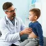 Medico che esamina delicatamente l'addome di un bambino in un ambulatorio luminoso, espressione concentrata ma rassicurante del medico, obiettivo 50mm, luce naturale dalla finestra.