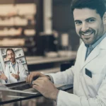 Immagine fotorealistica di un farmacista sorridente che partecipa attivamente a una videochiamata di gruppo su un laptop, simboleggiando l'engagement positivo in una comunità di pratica virtuale, sfondo sfocato di una farmacia moderna e luminosa, obiettivo prime 35mm, colori caldi e accoglienti, duotone seppia e blu per un tocco professionale ma umano.