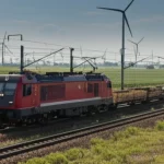 Immagine panoramica aerea di un treno merci moderno che attraversa un paesaggio misto di aree industriali e zone verdi con turbine eoliche, simbolo della connettività BRI e della sfida tra sviluppo e ambiente, wide-angle 20mm, sharp focus, luce del giorno chiara.