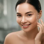 Ritratto di una donna asiatica sorridente con pelle luminosa e ringiovanita dopo un trattamento laser. Luce naturale morbida, sfondo leggermente sfocato, obiettivo prime 50mm, profondità di campo, colori caldi e naturali.
