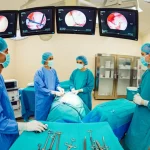 Fotografia dettagliata di una sala operatoria high-tech durante un intervento di chirurgia rettale mininvasiva, con monitor che mostrano immagini endoscopiche e un team chirurgico concentrato, obiettivo grandangolare 24mm, illuminazione chirurgica brillante, messa a fuoco nitida sull'azione centrale.