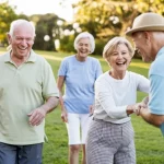 Un gruppo diversificato di anziani australiani attivi e sorridenti che partecipano a un'attività comunitaria leggera all'aperto in un parco, simboleggiando i benefici di un programma di cura restorative e la gioia di rimanere attivi. Fotografia con teleobiettivo zoom 100mm, luce naturale del tardo pomeriggio che crea un'atmosfera calda, catturando interazioni positive e movimento leggero tra i partecipanti.