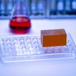 Fotografia macro, obiettivo 90mm, di un blocco di paraffina contenente tessuto suino (FFPE) accanto a una piastra PCR in un laboratorio di diagnostica veterinaria, illuminazione controllata, alta definizione, focus preciso sul campione tissutale, evocando la ricerca scientifica sulla Peste Suina Africana in Uganda.