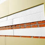 Immagine fotorealistica di una sezione trasversale di un muro esterno di una casa rurale cinese durante una ristrutturazione energetica. Si vedono i mattoni originali, uno strato spesso di pannelli isolanti (EPS) applicati esternamente, e la nuova finitura. Obiettivo 50mm, luce da cantiere che evidenzia i diversi strati, alta definizione dei materiali, focus sui dettagli tecnici della ristrutturazione.