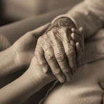 Immagine simbolica della fragilità negli anziani: una mano anziana e rugosa tenuta delicatamente da una mano più giovane, simboleggiando cura e supporto. Fotografia ritratto, obiettivo 50mm, profondità di campo, toni seppia e grigio duotone, luce soffusa.
