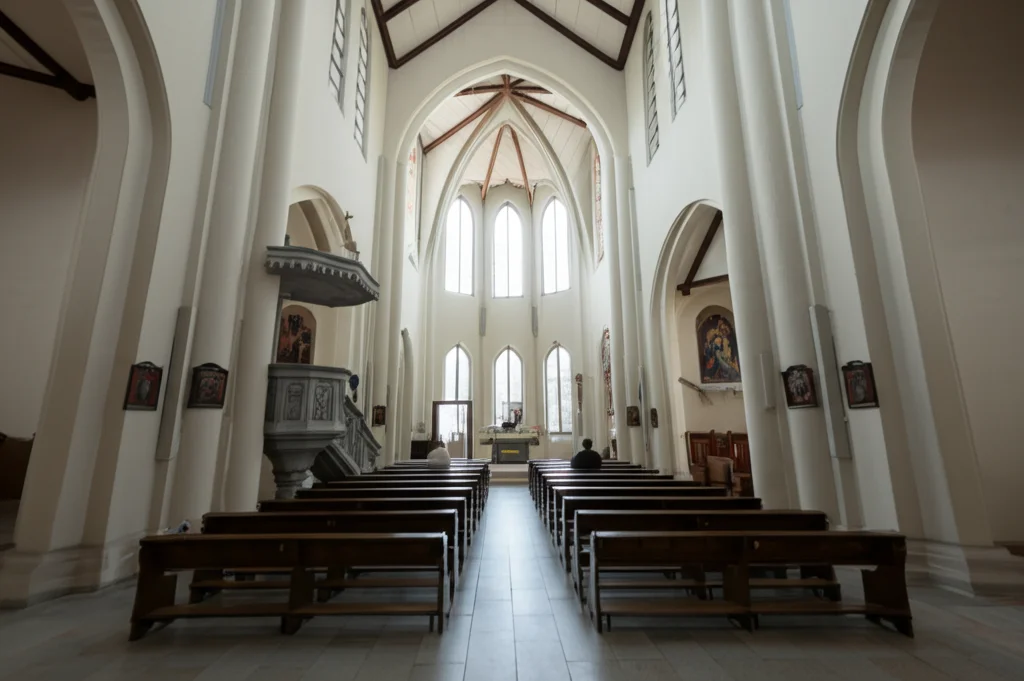 Fotografia grandangolare, 10mm, messa a fuoco nitida. Interno di una chiesa luminosa ma quasi vuota, con una singola figura seduta in una panca lontana. L'immagine evoca un senso di accoglienza formale ma anche di potenziale isolamento e la necessità di guardare oltre la semplice presenza fisica per una vera inclusione nella salute mentale.