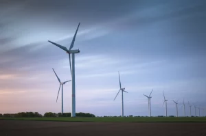 Turbine eoliche moderne che si stagliano contro un cielo danese al tramonto, simbolo di energia rinnovabile e impatto economico locale, fotografia paesaggistica, obiettivo grandangolare 20mm, lunga esposizione per nuvole soffici.