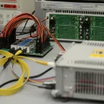 Banco di prova sperimentale per motore DC con scheda controller dSPACE DS1104 visibile, cavi collegati, focus sull'hardware di controllo avanzato, illuminazione da laboratorio chiara e definita, obiettivo macro 60mm, alta definizione dei componenti elettronici.