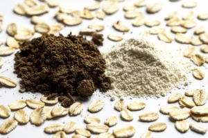 Composizione fotografica still life che mostra la trasformazione della polpa d'avena: da un mucchietto umido e scuro a sinistra, a polvere fine e chiara a destra, con fiocchi d'avena sparsi intorno. Illuminazione drammatica controllata, obiettivo macro 100mm, alta definizione, focus sulla texture.