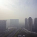Immagine evocativa dell'impatto dell'inquinamento atmosferico sulla salute pubblica in Cina, con particolare riferimento all'ictus ischemico. Fotografia di un panorama urbano cinese con smog visibile, obiettivo grandangolare 18mm, lunga esposizione per catturare il movimento delle nuvole di smog, messa a fuoco nitida sull'orizzonte.