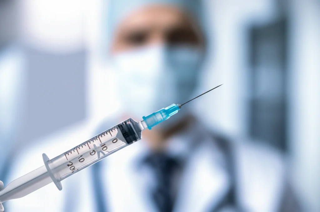 Primo piano di una siringa con vaccino RZV pronta per l'iniezione, sfondo sfocato di un ambiente medico. Obiettivo macro 90mm, alta definizione, illuminazione controllata e clinica.