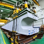 Fotografia realistica di una imponente trave a I in calcestruzzo precompresso lunga 35 metri all'interno di un laboratorio di prova, sottoposta a un carico di flessione. Utilizzo di un obiettivo grandangolare 18mm per catturare l'intera scena, illuminazione controllata da laboratorio che evidenzia la struttura e i sensori applicati. Si vedono i martinetti idraulici che applicano il carico e la strumentazione di misura. Focus nitido sulla parte centrale della trave.
