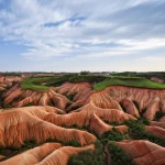 Veduta aerea del paesaggio di loess vicino a Xi'an, Cina, con evidenti segni di erosione e potenziali aree di instabilità geologica. Wide-angle lens, 15mm, luce naturale del tardo pomeriggio, sharp focus, long exposure per nuvole soffici nel cielo.