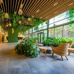Interno luminoso e moderno di una lobby di green hotel con piante rigogliose, materiali naturali come legno e pietra, luce naturale abbondante che entra da grandi finestre. Obiettivo grandangolare 24mm per mostrare l'ambiente accogliente, ecologico e spazioso.