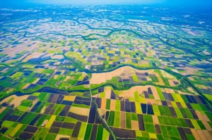 Immagine aerea, scattata con obiettivo grandangolare 20mm, della Cina nord-orientale che mostra il mosaico complesso di terreni coltivati (risaie irrigate e campi aridi) che si insinuano in vaste zone umide naturali (paludi e fiumi serpeggianti). La transizione netta tra i due usi del suolo è evidente. Messa a fuoco nitida su tutto il paesaggio, lunga esposizione per ammorbidire eventuali nuvole basse, colori vividi ma realistici sotto la luce del sole di mezzogiorno.
