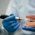 Ritratto professionale di un dentista che utilizza un manipolo laser odontoiatrico Nd:YAG su un modello dentale dimostrativo, focus sul fascio di luce laser rosso visibile, profondità di campo ridotta per isolare il soggetto, obiettivo 50mm prime, illuminazione da studio controllata e professionale, sfondo neutro sfocato.