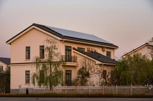Immagine fotorealistica di una tipica abitazione suburbana nella provincia di Jiangsu, Cina, con pannelli solari sul tetto e un piccolo giardino curato, illuminata dalla luce calda del tramonto. Fotografia architettonica, obiettivo 24mm, luce dorata, alta risoluzione, dettagli nitidi sull'edificio e sulla vegetazione circostante.