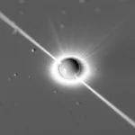 Macro fotografia, lente 100mm, primo piano estremo di un fascio laser a femtosecondi che colpisce con altissima precisione una singola microsfera di polistirene (15µm) su una superficie di vetro pulita, la sfera inizia a vaporizzare creando una piccola onda d'urto visibile, illuminazione da studio controllata per massimo dettaglio, high detail, precise focusing.