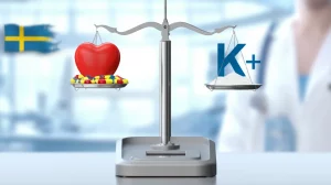 Immagine concettuale fotorealistica: una bilancia medica stilizzata. Su un piatto, un cuore rosso sano protetto da capsule di farmaci RAASi. Sull'altro piatto, un simbolo chimico del potassio (K+) tenuto saldamente sotto controllo da una polvere che rappresenta i leganti del potassio. Lo sfondo è un ambiente clinico moderno e luminoso, forse con elementi che richiamano la Svezia (colori bandiera stilizzati). Obiettivo 50mm, profondità di campo media per mantenere a fuoco entrambi i piatti della bilancia.