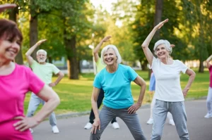 Gruppo diversificato di persone anziane che partecipano attivamente a una sessione di ginnastica dolce all'aperto in un parco cittadino. Alcuni sorridono, altri sono concentrati sull'esercizio. Luce solare diffusa del tardo pomeriggio, colori naturali, obiettivo zoom 24-70mm catturando l'interazione sociale e il movimento fluido, stile fotorealistico e positivo.