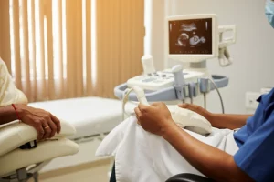 Immagine simbolica di una ecografia fetale su uno schermo in una clinica moderna ma in un contesto sud-asiatico, rappresentando la speranza e la tecnologia della gravidanza assistita. Obiettivo 50mm, profondità di campo, luce calda.