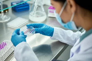 Ricerca genetica sul diabete gestazionale: una scienziata del sud-est asiatico osserva attentamente una piastra multi-pozzetto contenente campioni di DNA in un laboratorio moderno e ben illuminato. Lente macro 90mm, alta definizione, illuminazione precisa sui campioni, sfondo leggermente sfocato con attrezzature da laboratorio.