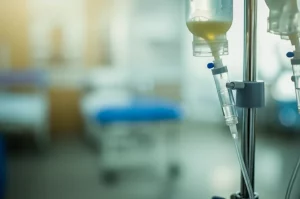 Primo piano di una flebo di Rituximab in un ambiente clinico luminoso, obiettivo macro 80mm, messa a fuoco precisa sui dettagli della sacca e del tubo trasparente con il farmaco, illuminazione controllata, sfondo leggermente sfocato per enfatizzare la flebo.