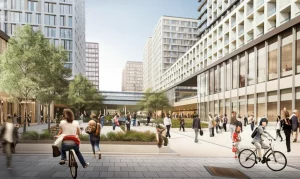 Immagine fotorealistica di un moderno quartiere urbano progettato secondo i principi del Next-Gen TOD. Si vede una stazione di trasporto pubblico integrata con edifici residenziali e commerciali ad uso misto, ampi spazi pedonali, piste ciclabili, verde urbano e persone che interagiscono. Scatto con obiettivo zoom 24mm, luce del tardo pomeriggio, profondità di campo che mostra sia i dettagli architettonici che la vita urbana.