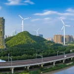 Immagine paesaggistica grandangolare, 10mm, che mostra un panorama cinese moderno e sostenibile: grattacieli con tetti verdi, turbine eoliche su colline vicine, treni ad alta velocità e un fiume pulito, lunga esposizione per nuvole soffici, messa a fuoco nitida.