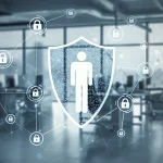 Immagine concettuale di sicurezza informatica aziendale: una figura umana stilizzata al centro di una rete di connessioni digitali protetta da uno scudo trasparente, sullo sfondo un ambiente ufficio moderno e luminoso. Obiettivo 50mm, profondità di campo ridotta per mettere a fuoco la figura centrale e lo scudo, colori corporate blu e argento duotone.