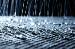 Primo piano fotorealistico di gocce d'acqua pura che filtrano attraverso una membrana TFC per osmosi inversa, obiettivo macro 85mm, alta definizione, illuminazione laterale drammatica che evidenzia la texture rugosa della membrana poliammidica e la limpidezza cristallina dell'acqua permeata.