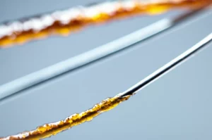 Immagine fotorealistica, lente macro 90mm, primo piano di un filo di sutura in seta innovativo rivestito con chiodo di garofano/gelatina, evidenziando la texture e il rivestimento, leggermente avvolto su una superficie sterile, alta definizione, messa a fuoco precisa, illuminazione medica soffusa.