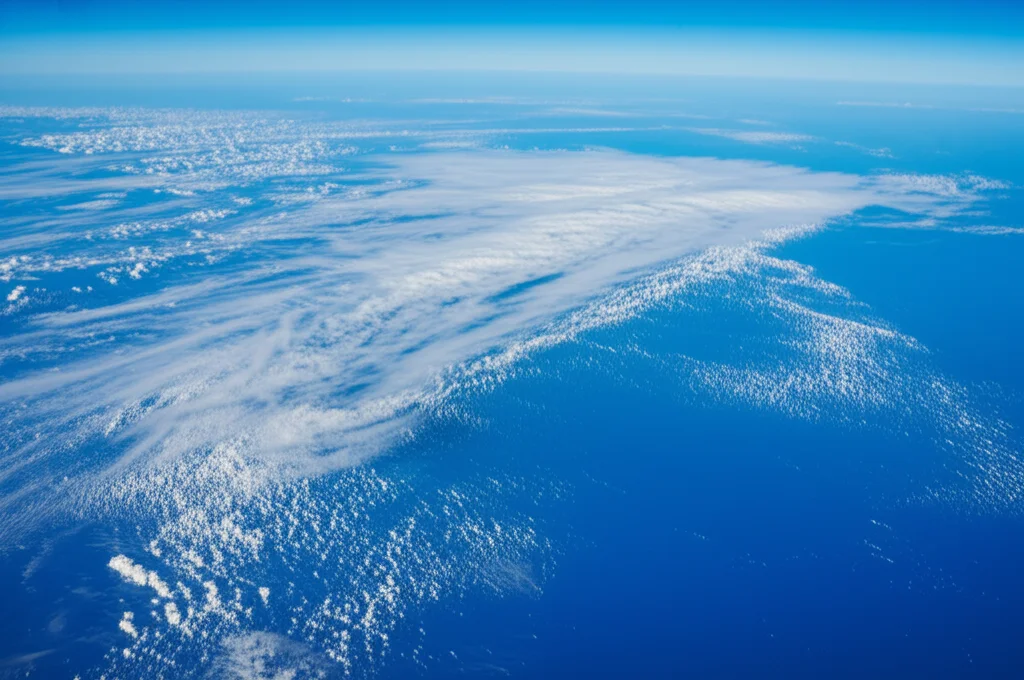 Vista aerea dell'Oceano Atlantico equatoriale con pattern di nuvole convettive (ITCZ) che si estendono sull'acqua blu profondo, evidenziando l'interazione atmosfera-oceano, obiettivo grandangolare 18mm, luce solare diffusa, messa a fuoco nitida sull'orizzonte.