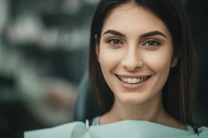 Ritratto di una donna sorridente dopo un trattamento ortodontico complesso, luce naturale morbida, sfondo leggermente sfocato per enfatizzare il viso felice. Obiettivo da ritratto 85mm, profondità di campo ridotta.