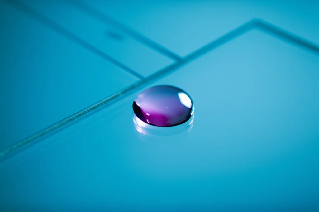 Primo piano macro di una goccia di sangue su un vetrino da laboratorio, illuminazione controllata, alta definizione, lente macro 100mm, focus preciso sulla goccia, che simboleggia l'analisi dei biomarcatori come l'indice TyG.