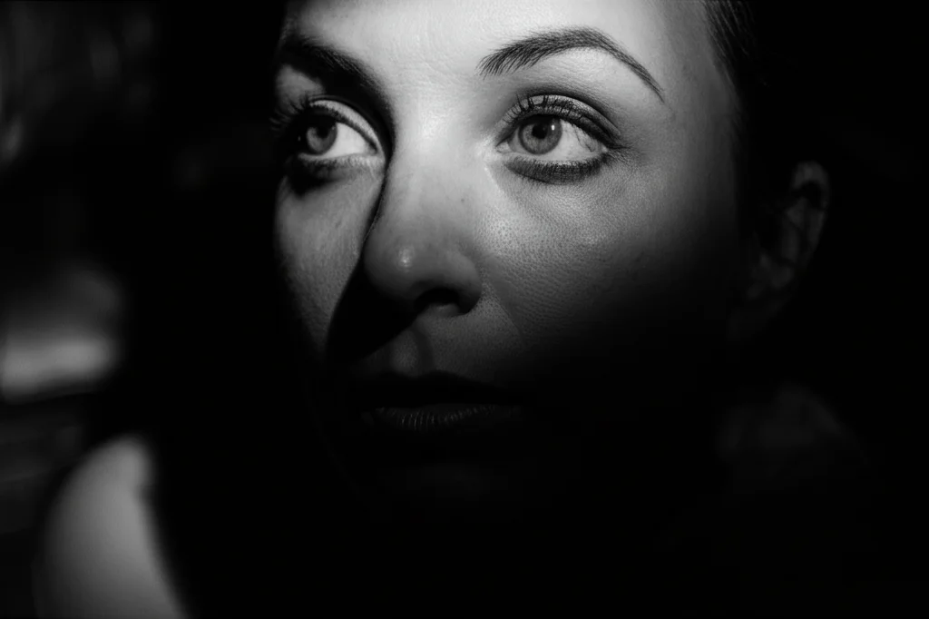 Ritratto di una persona concentrata, sguardo pensieroso verso l'interno, 35mm, bianco e nero, profondità di campo ridotta, illuminazione drammatica stile film noir, che simboleggia l'introspezione della metacognizione.