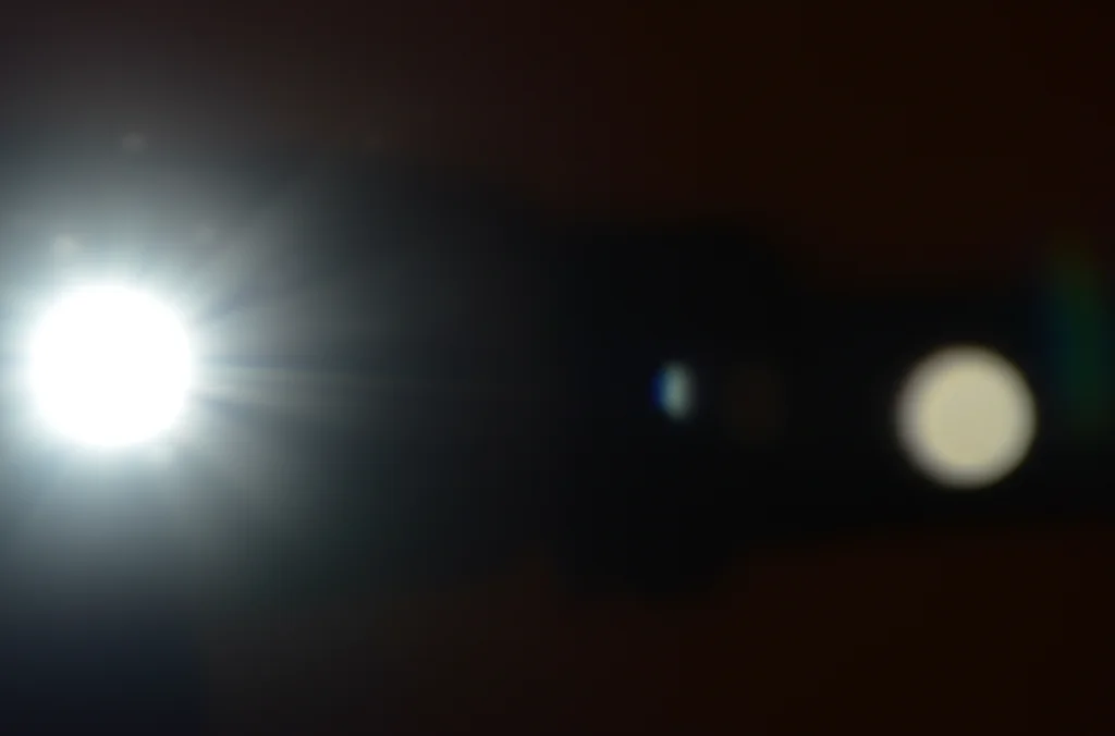 Visualizzazione astratta di due punti luce, uno a sinistra leggermente prima dell'altro a destra su uno sfondo scuro, obiettivo macro 90mm, alta definizione, messa a fuoco precisa sul punto sinistro, illuminazione controllata per evidenziare la sequenza temporale asimmetrica.