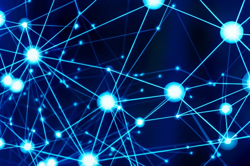 Immagine fotorealistica di una rete complessa e luminosa di nodi interconnessi di varie dimensioni (grandi, medi, piccoli) che fluttuano in uno spazio astratto blu scuro, rappresentando un sistema di governance policentrico e multilivello per l'IA. Obiettivo grandangolare 15mm, lunga esposizione per creare scie luminose tra i nodi, messa a fuoco nitida.